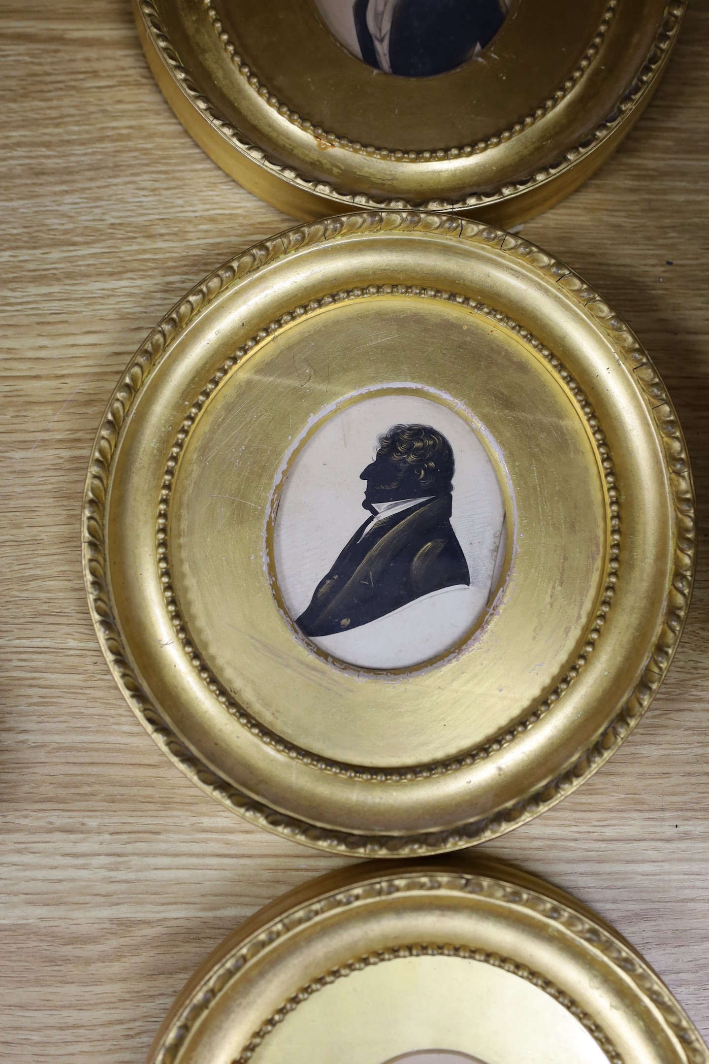 Victorian School, cut paper heightened with bronze, Silhouette of a gentleman, 8 x 6.5cm, with two similar silhouettes